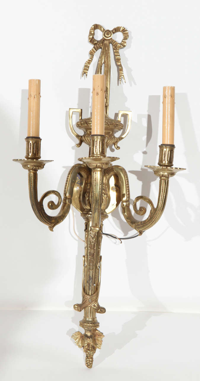 A wonderful pair of French Hollywood Regency brass sconces. Each has three light sockets, Excellent detail on the design including the bowed tops.