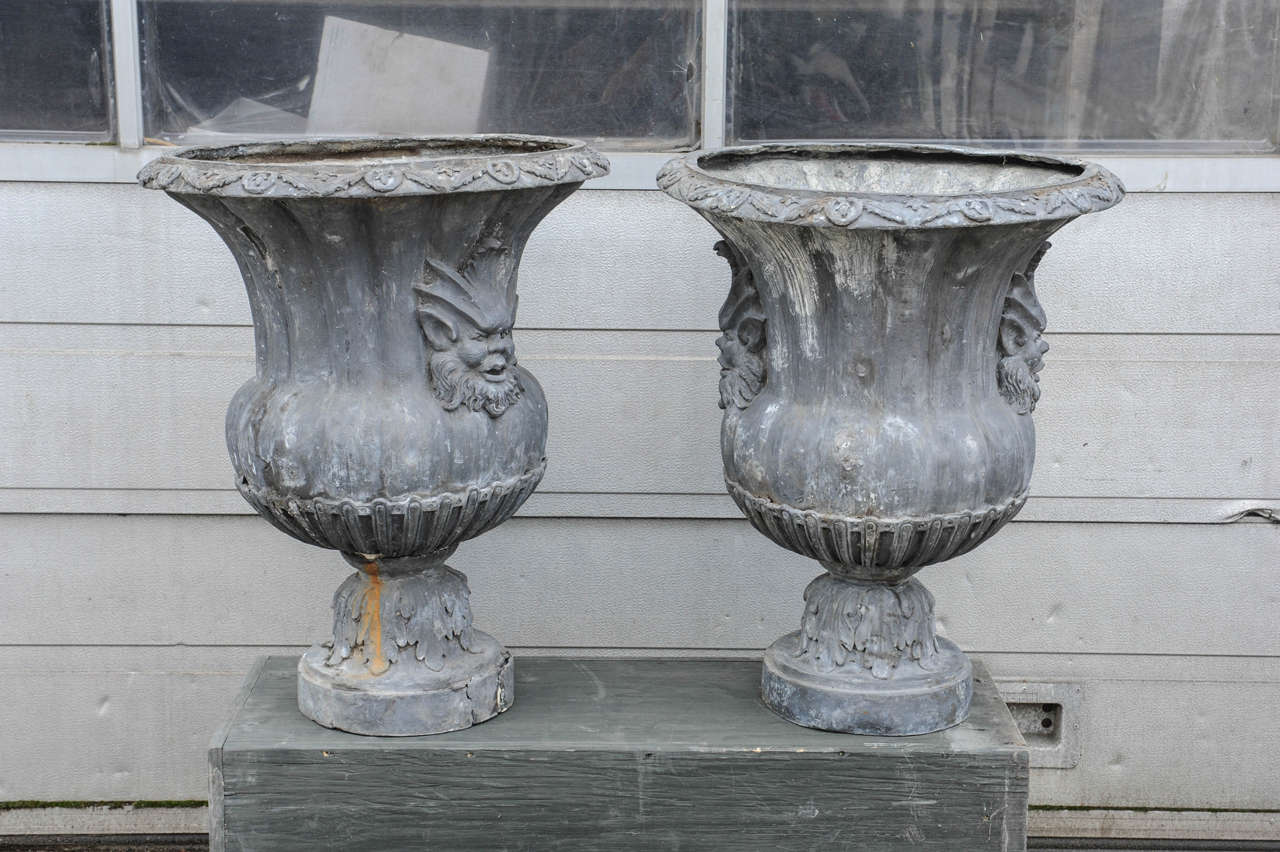 Vases with faux masks, the rim and raised circular base with Acanthus leafs.