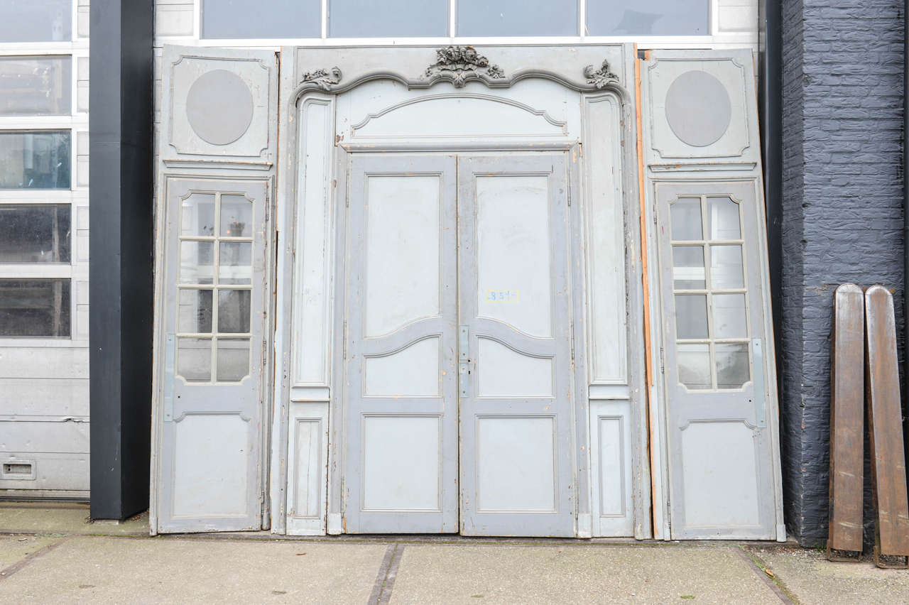 Boiserie à quatre portes en chêne sculpté Louis XIV du XVIIIe siècle, avec patine d'origine en peinture grise. 2 panneaux avec des portes vitrées (placards) dans leurs vitres d'origine. 1 panneau avec une paire de portes doubles.

Dimensions :