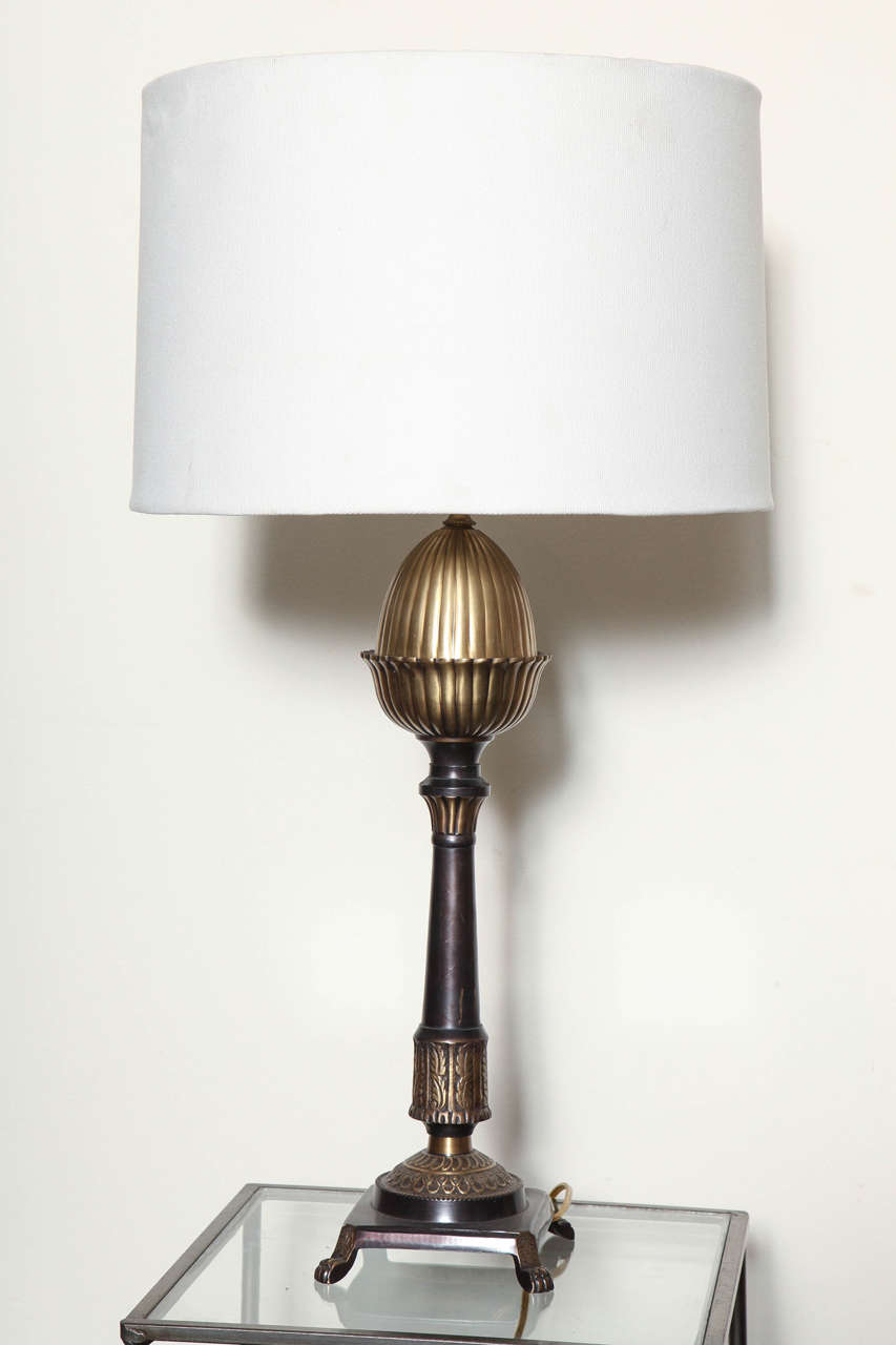 A stately pair of Regency table lamps. Reeded sculptural tops. Embossed legs. Rich satin brass and antique bronze finish. 5 inches tall, bottom base is 4 inches wide. Shown with 15 x 16 x 91/2 shade not included. Overall height 24 1/2 tall. 3 way