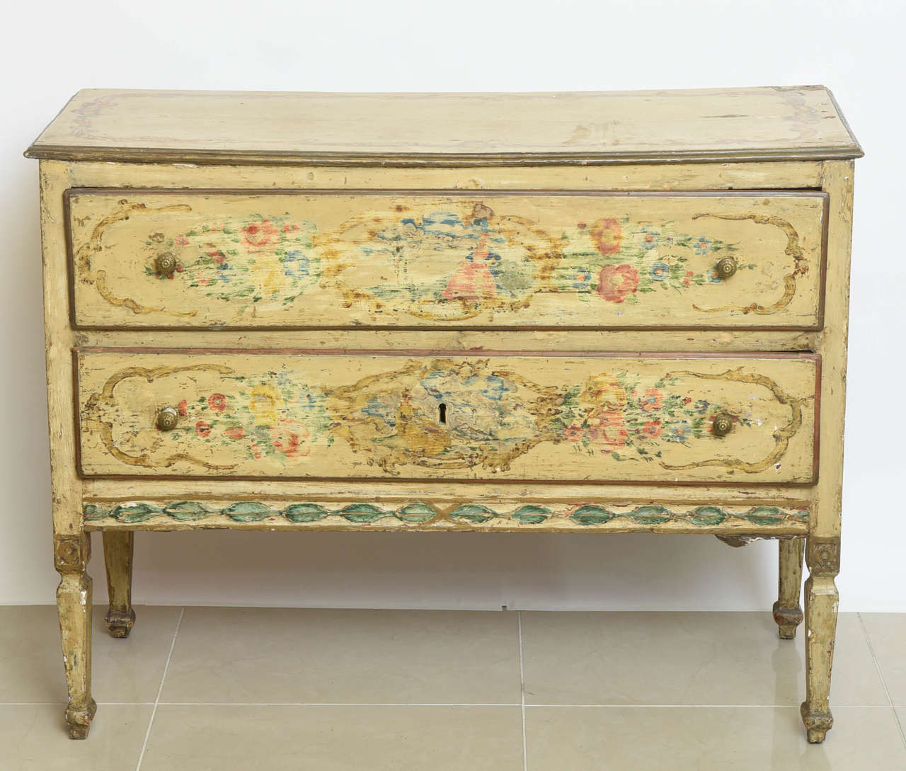 The rectangular top above two drawers and paneled sides above square tapering legs, overall painted in a pale yellow ground with floral and figural scenes, original paint not refreshed.