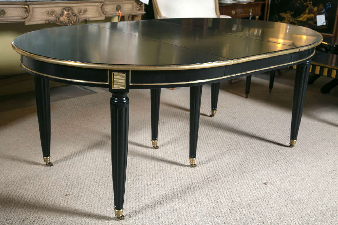 French Louis XVI style ebonized Jansen four-leaf dining table. This one of a kind dining table has three skirted and one none skirted (later addition) table leaves. Each 20.5 inches wide. The tapering Louis XVI style legs having solid bronze casters