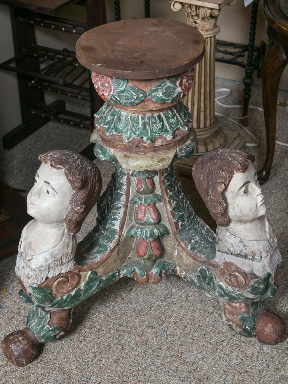 All wooden table base with three carved heads that culminate in the ball feet. Leaves and fruit are carved in the legs. The piece retains a later 19th century paint. To be used as a table base for a glass top, or a figural stand. The base for