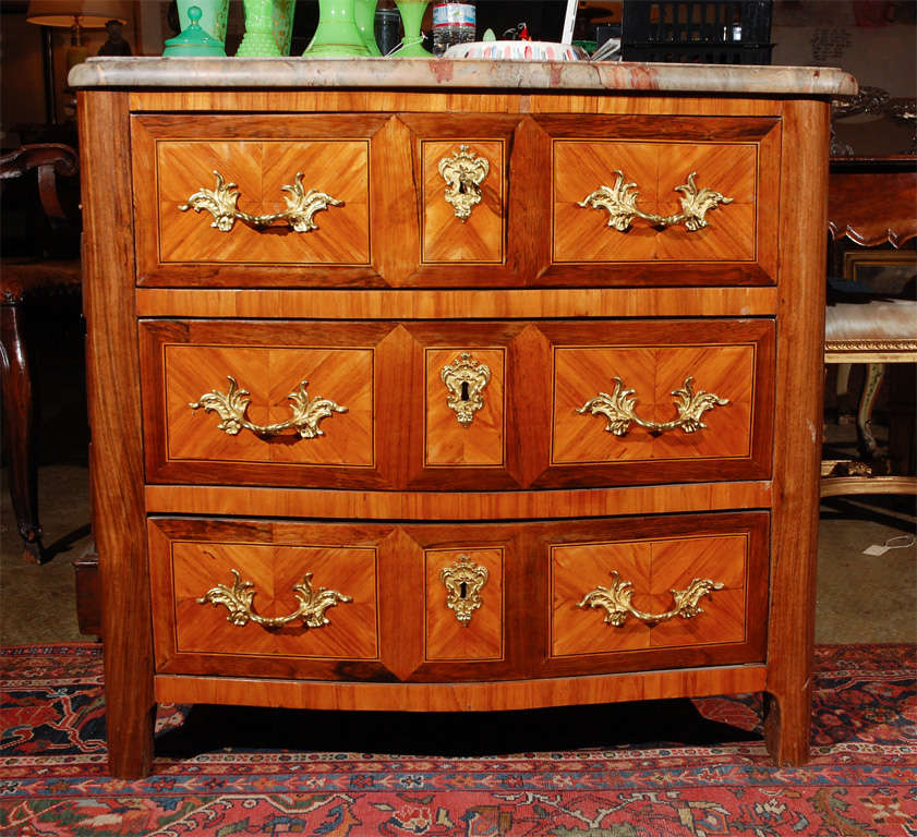 Striking, veneered and inlaid, four drawer, faux paneled, kingwood and rosewood, French commode surmounted by a polished marble top and finished with gilt bronze drawer pulls and escutcheons.