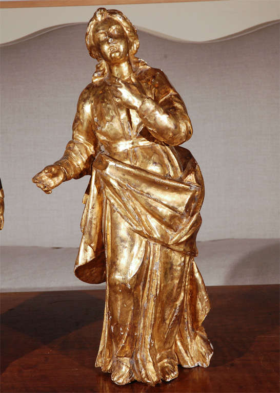 An expressive pair of hand carved, gessoed and 22-karat gold gilded women in deeply carved drapery. Taken from a larger grouping, these figures were possibly attendants of the cross.
