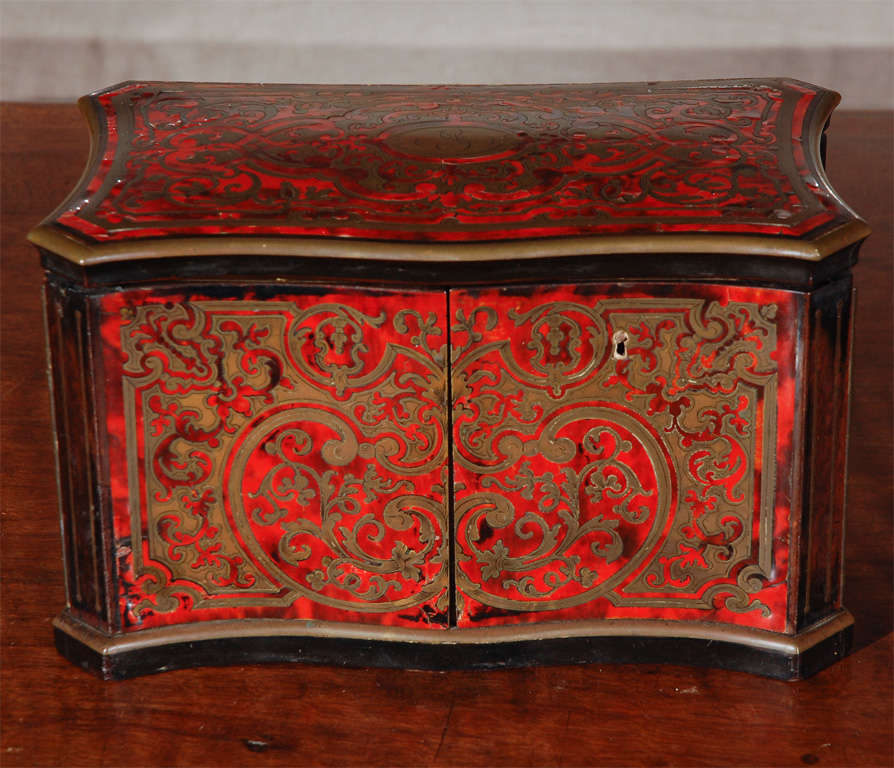 Red tortoise-shell, tea-caddy with intricate, bronze inlay.