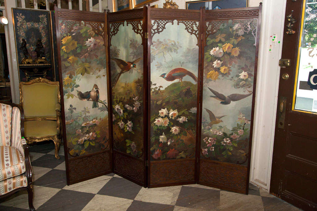 A WOOD FRAMED 4  PANEL SCREEN, PAINTED ON CANVAS WITH BIRDS AND FLOWERS. IN A BLIND AND OPEN FRETWORK SCREEN WITH CARVED LOWER PANELS. THE HINGES ARE  2 WAY. THE BACK NOW COVERED WITH FABRIC IN NEED OF REPLACEMENT. THERE ARE  FOUR  BASES THAT CAN BE