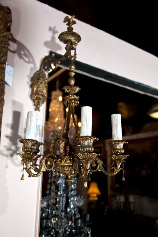 A PAIR OF 5 LIGHT  SCONCES IN THE FORM OF  CHANDELIERS. A SATYR MASK PLATE HOLDS  THE ARM FROM WHICH HANGS THE  5 LIGHT FIXTURE. BIRD FINIAL SURMOUNTS  IT ALL. CURNED ARMS WITH FOLIATE DECORATION.