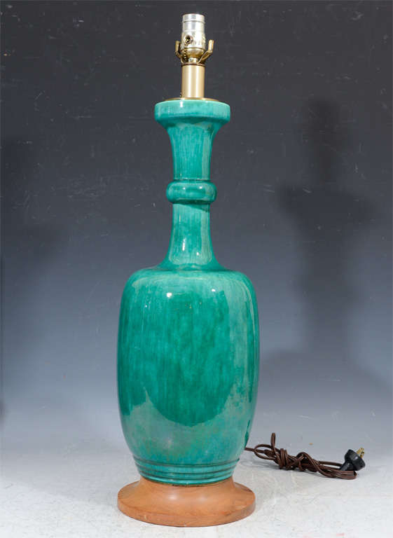 A pair of ceramic lamps on turned wood bases in a vibrant teal-green.