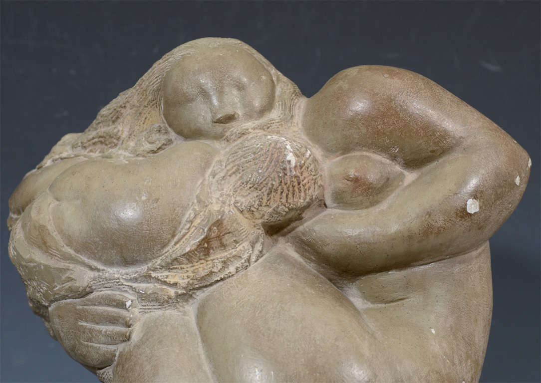 An abstract sculpture depicting a nude female figure cradling a child. The piece is similar to the works of famed sculptor Jose de Creeft and is signed with the initials MPI. It has been mounted to an ebonized wood base. The piece has age