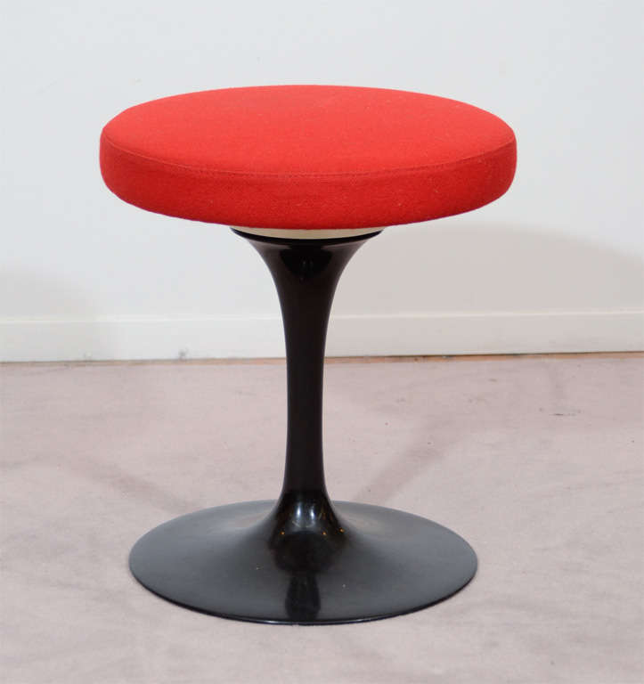 A vintage stool by Eero Saarinen for knoll. The piece has a black base and original red upholstery.