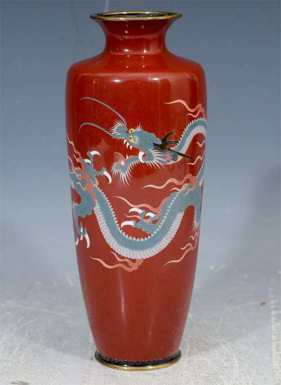 A 20th century Japanese vase in cloisonne with blue dragons depicted on a red background.