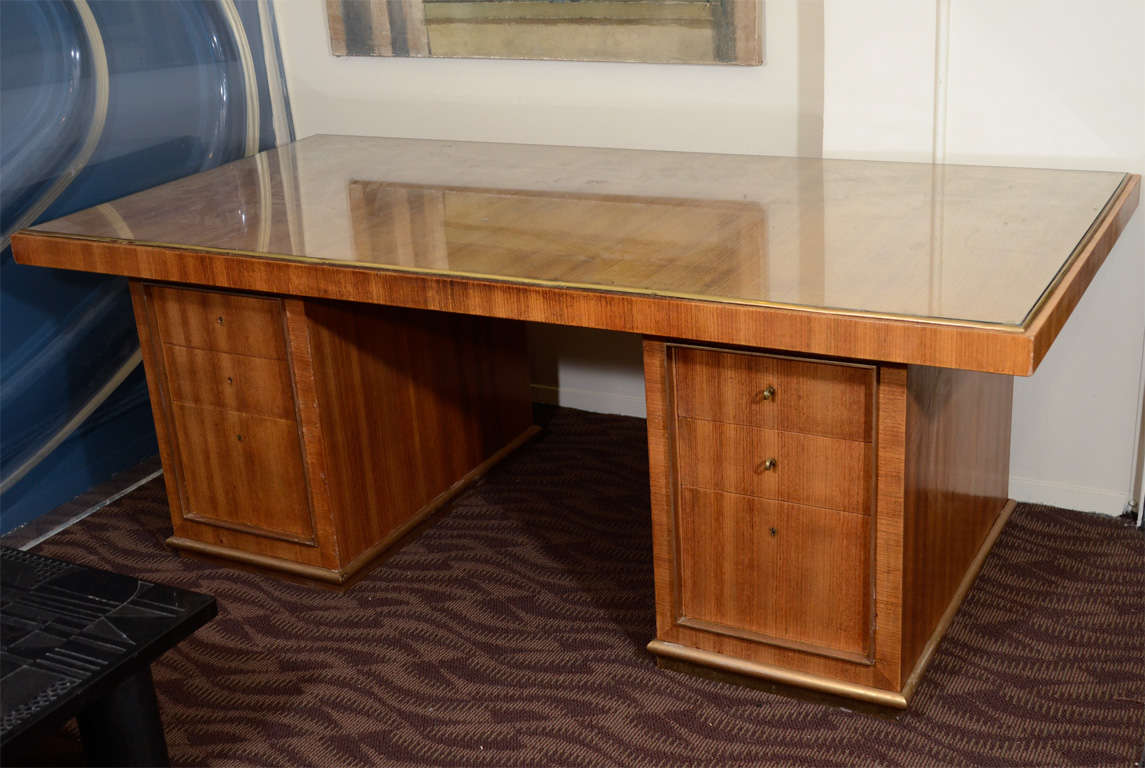An executive desk with a bronze framed glass top and six drawers. The piece is by Jean Royere and retains the Gouffé Paris label on the drawer interior