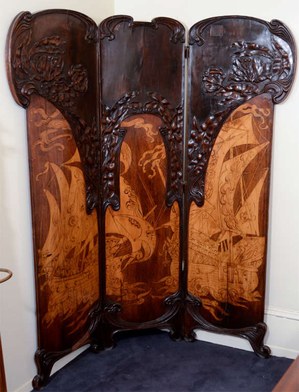 An Italian folding screen in the Stile Liberty (Liberty Style; the Italian Art Nouveau) by the Florence furniture maker firm of Girard and Cuttler. The piece is in walnut, mahogany and satinwood with floral arches above an inlaid nautical scene with