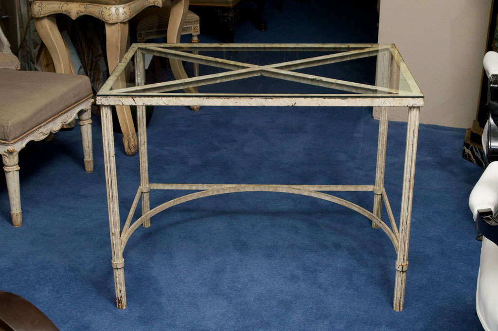 The rectangular glass top with x-shaped supports raised on reeded legs joined by an arched stretcher.