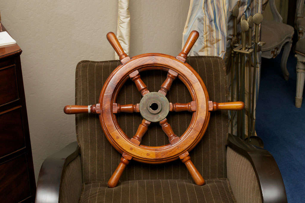 The high glossed hardwood wheel with six turned spokes converging at a patinated casted brass nave.  From sailing yacht built in 1934.