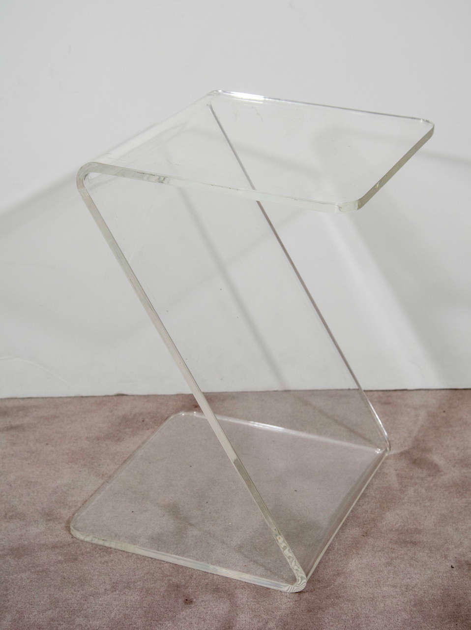 A petite vintage side table composed of clear lucite in a zig-zag form.