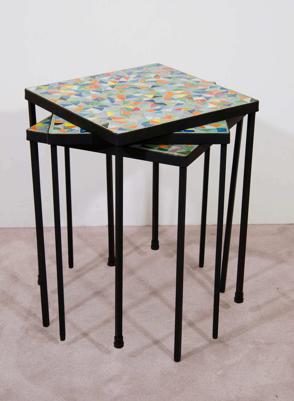 A vintage set of three stacking tables with colorful Murano mosaic tiled surfaces and iron frames.