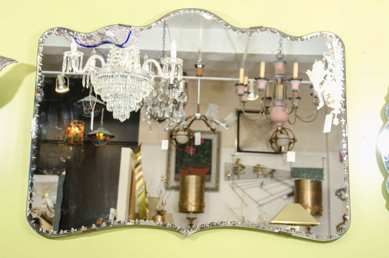 A Hollywood Regency scalloped mirror with beveled diamond and oval detail around the edge.