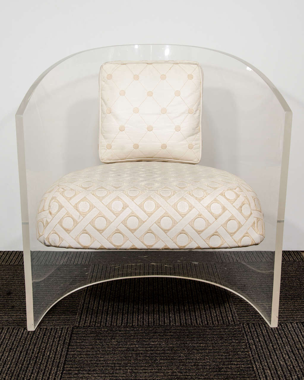 A vintage pair of clear Lucite chairs with white, diamond patterned upholstery.