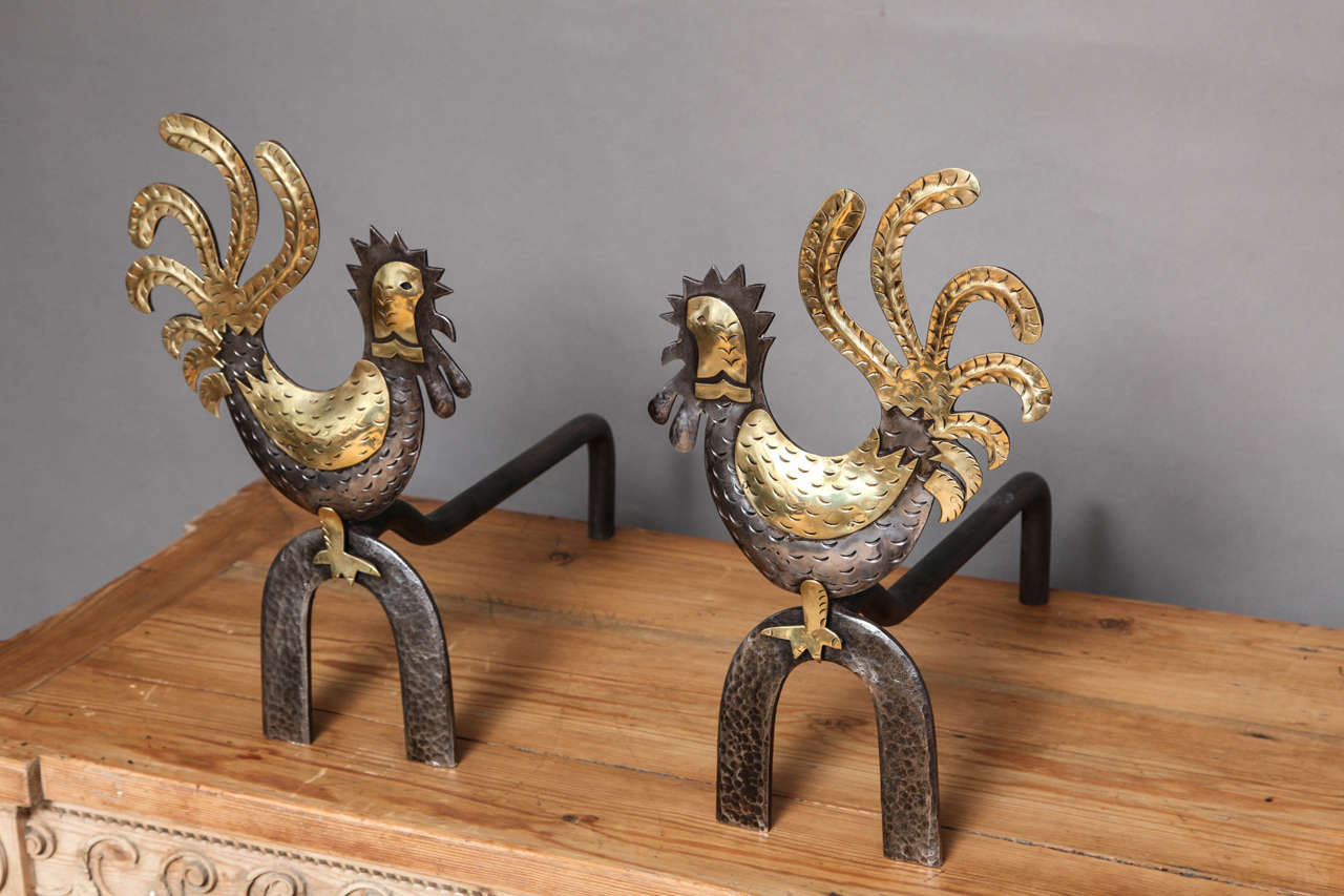Charming pair of mid 20th Century mixed metal andirons in the form of crowing roosters, the heads, tails, wings and feet wrought in hammered brass, the combs, waddles, beaks, bodies and bases in hammered steel, the whole having whimsical form and
