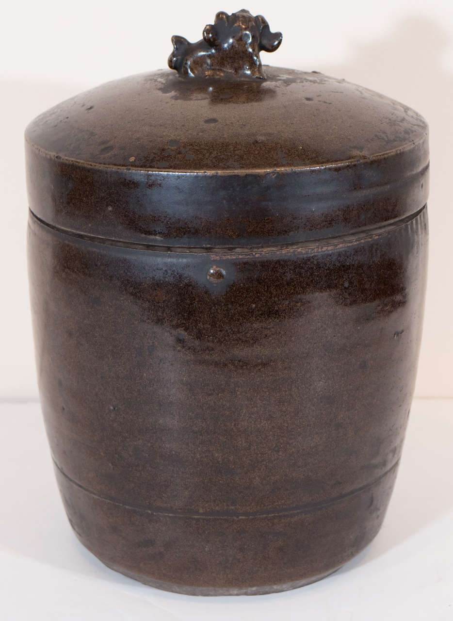 An antique covered ceramic oil jar with decorative mythical animal on lid. From Shanxi Province, circa 1900.
    