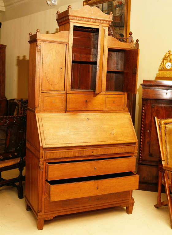 Fall-front country secretary cabinet in light oak, with carved dental moldings, corinthian columns and interior detailled with small drawers. Three drawers below. Danish, mid-19th century.