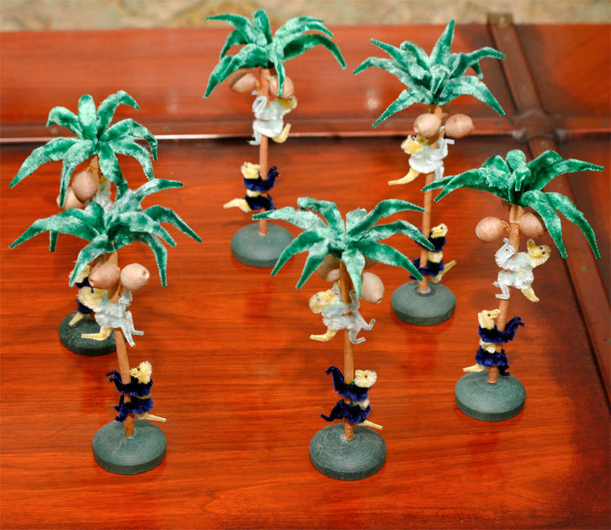 Two sets of whimsical monkeys playing in palm trees of pipe cleaner, paper mache and wood designed as table decorations for dinner parties. The two sets are in the original box and date from the  mid 1930's. The palm trees are centered on a small