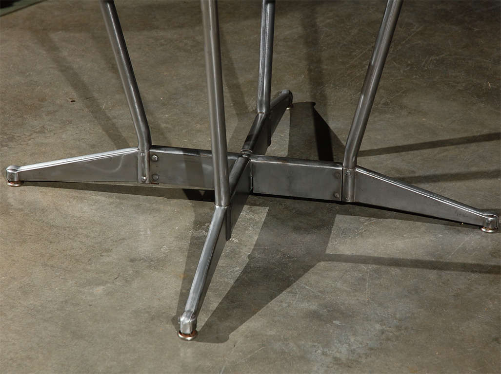 An American table, circa 1950's, having a glass top surface and metal base. This "Amerex" table is by "American Seating" and is thought to have been used in a commercial environment.