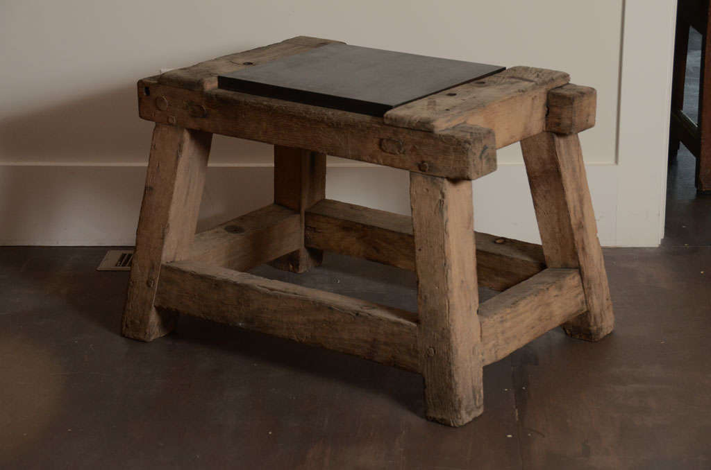 Vintage table made of rustic wood with beautiful patina - a solid bronze plate sits on the top.