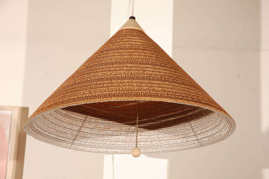 Eye-catching pendant lamp constructed of concentric cardboard rings suspended from wood. This ceiling light is great hanging over a breakfast table, desk or to light up a dark corner.