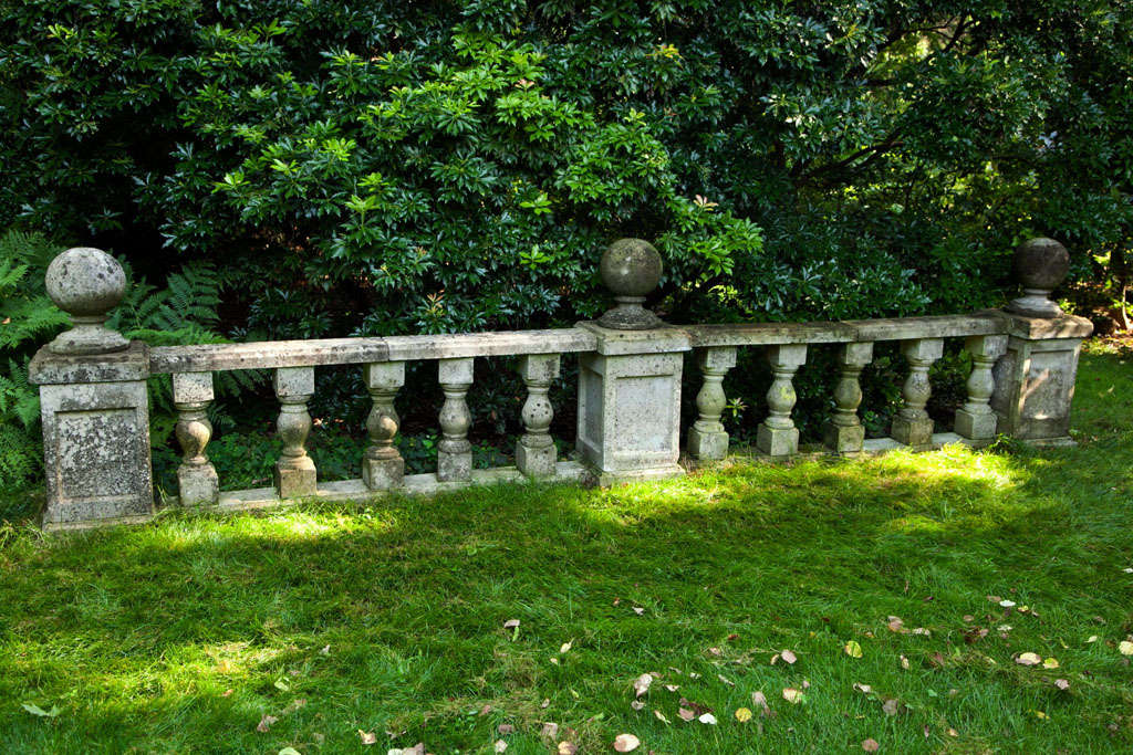 A length of composition stone balustrade punctuated by three plinths with ball finials.
