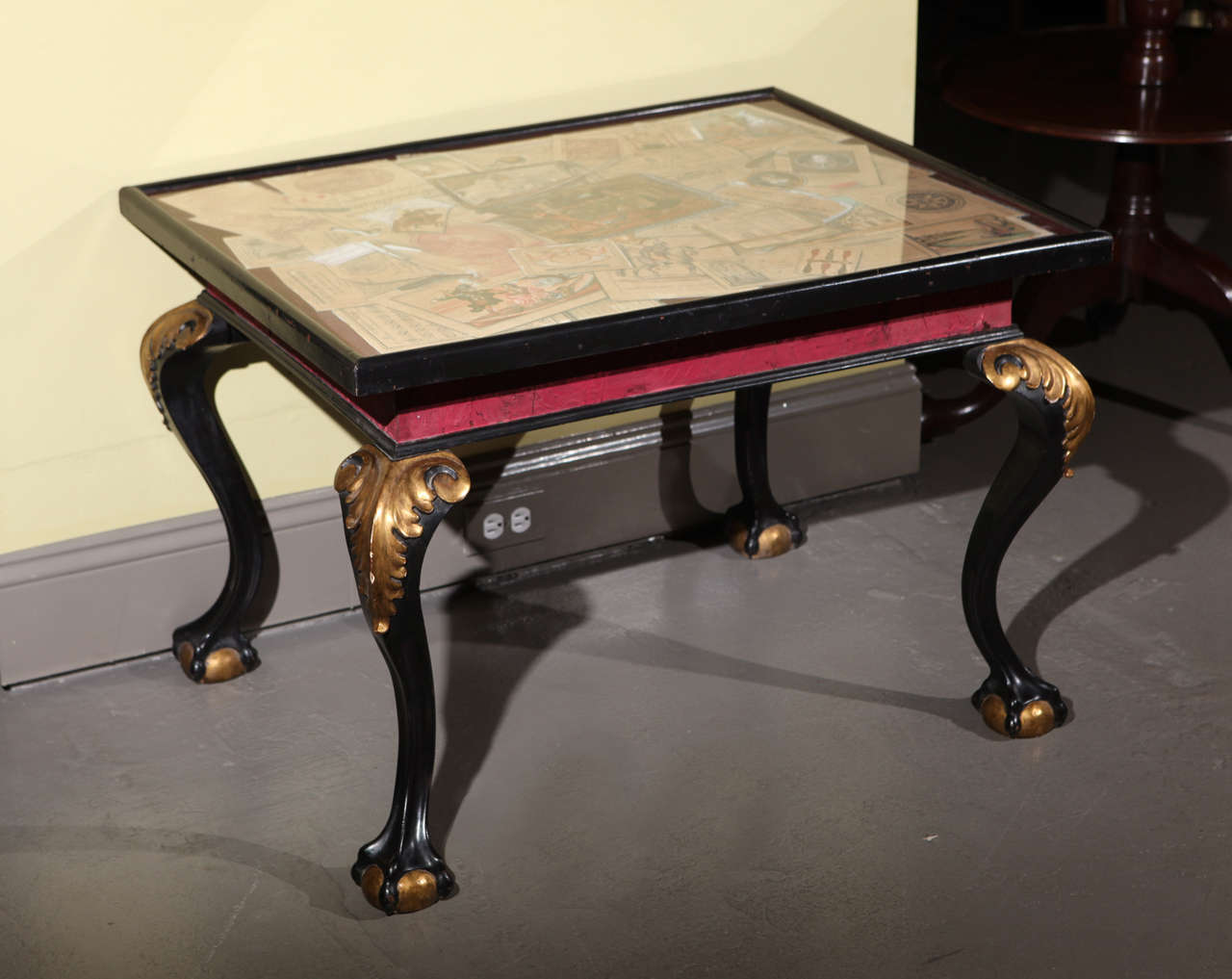 A Spanish Tea Table with ebonized and parcel gilt cabriole legs supporting a tray top beautifully painted in Trompe l'Oeil featuring a grouping of various prints, cards and accessories, c. 1850