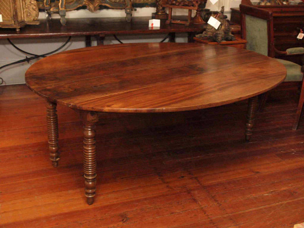A drop leaf dining table with interesting and well-turned legs ending in toupie feet.