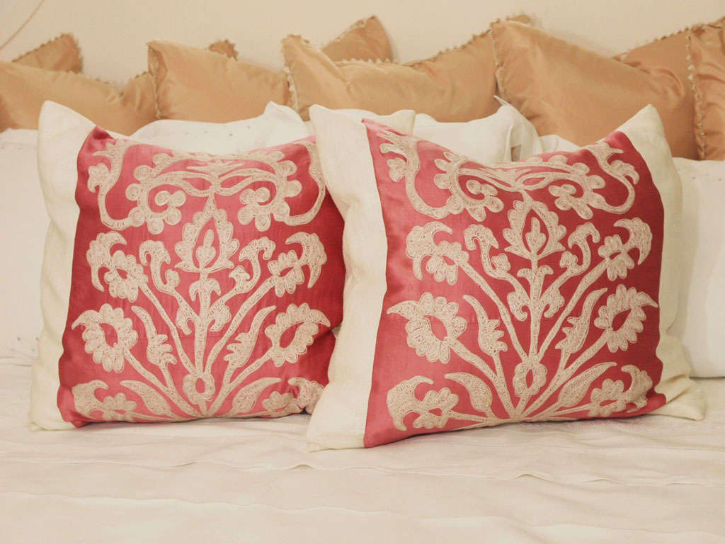 Pair of vintage Suzani pillows in cream embroidery on pink adras, ground bordered and backed with cream linen. Overlap closure ties.