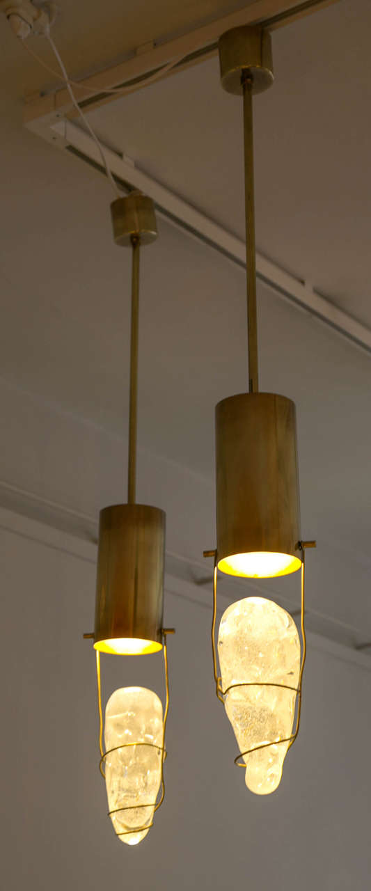 A pair of ceiling fixtures, 
Each lamp is composed of a block of glass hanging from a brass structure. 
Designed by Angelo Brotto for Esperia.
circa 1990, Italy.

H total : 102 cm
H: brass lamp + glass : 45 cm