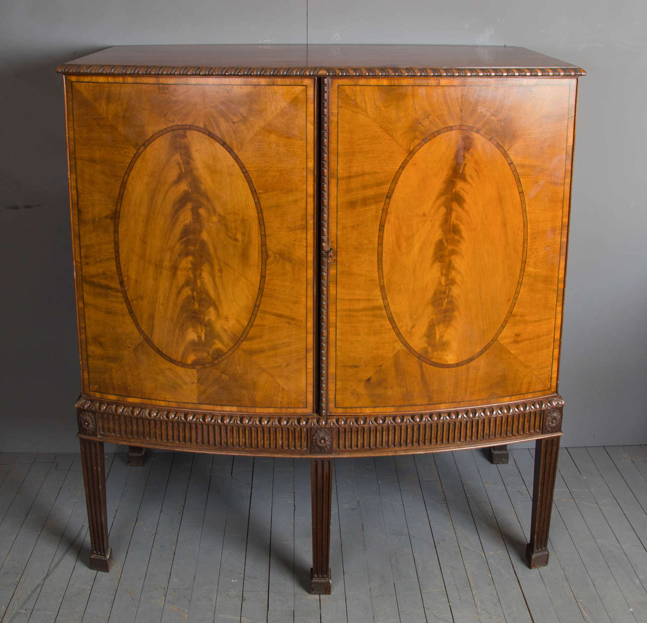 Mahogany Sheraton Revival style cabinet by Howard and Sons. This very handsome and well-proportioned cabinet was made by Howard and Sons, a well-known cabinet maker of the period. The cabinet features a two-door bow front and is supported on five
