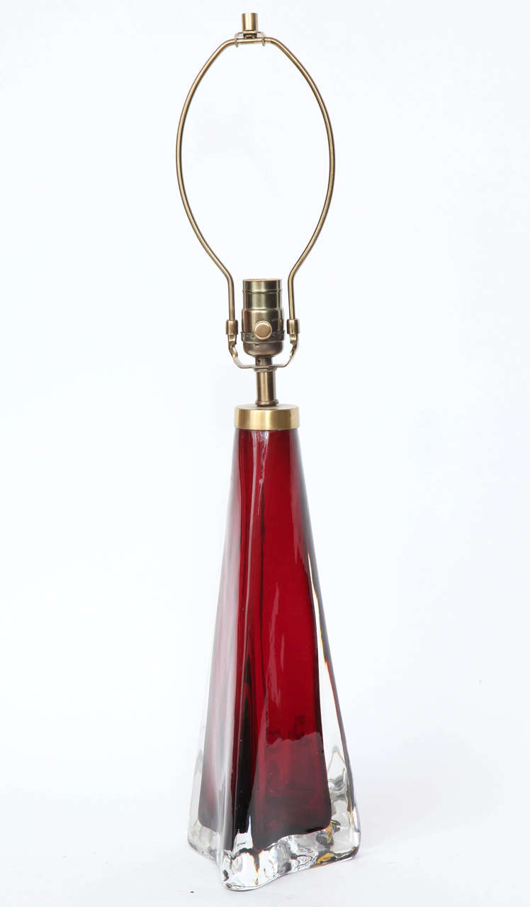 Classic triangular form cranberry red crystal lamp with a polished clear crystal overlay, designed by Carl Fagerlund for Orrefors. Lamp has been rewired for use in the USA with satin brass socket and clear cord.