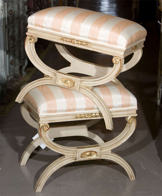 Painted and parcel-gilt X-based stool with stretcher, upholstered in striped fabric.