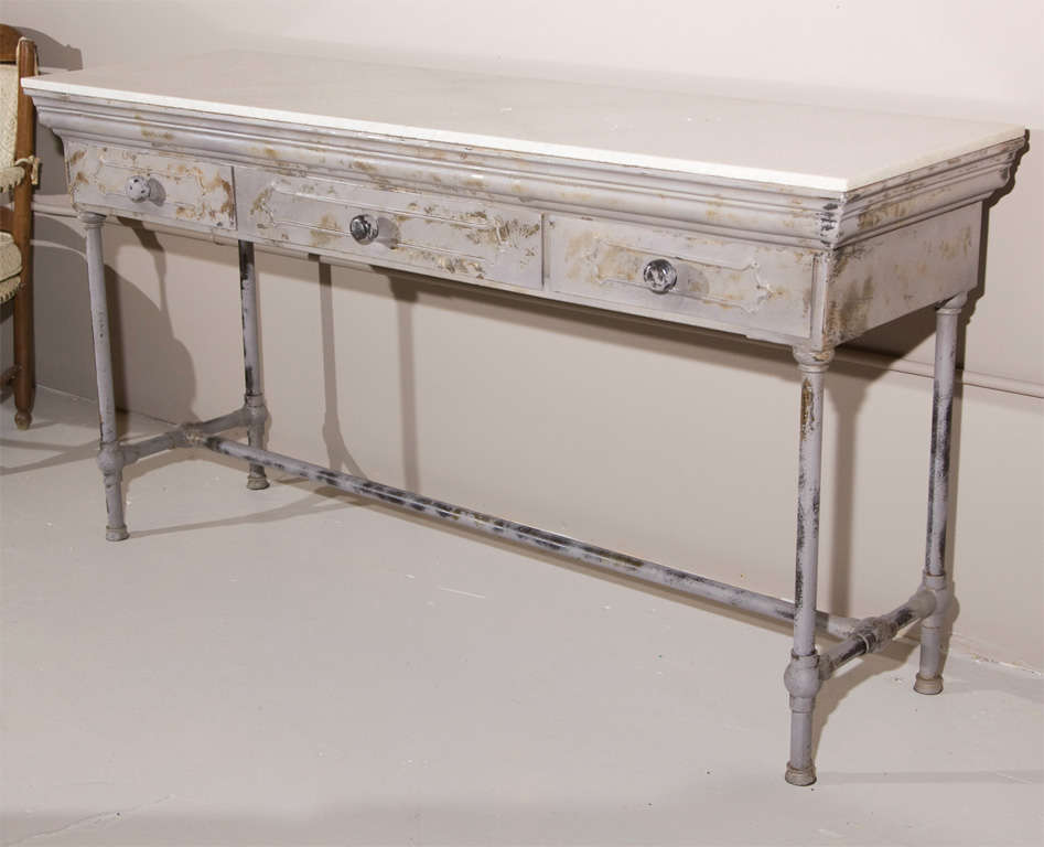 An industrial metal console table with white rectangular marble top, three drawers. The marble top having been broken in two pieces.