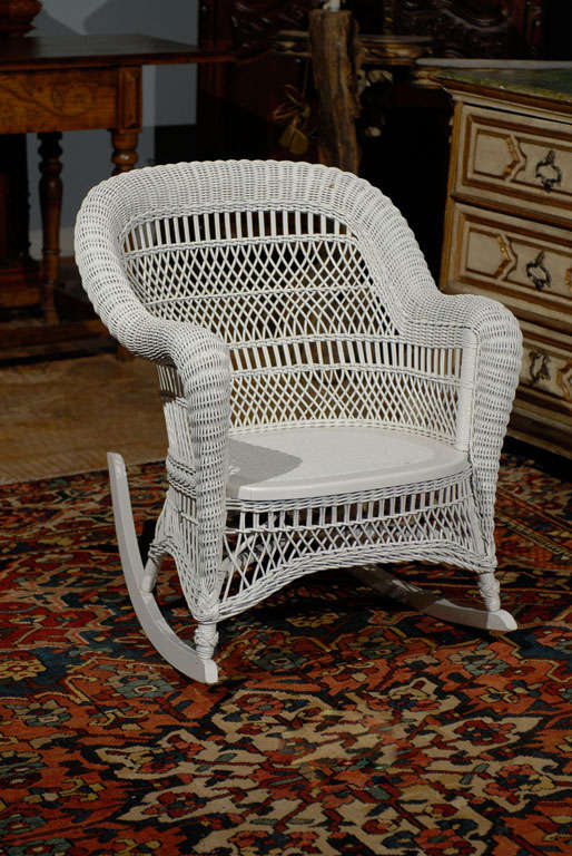 A wonderful wicker rocking chair with arms and an arched back.