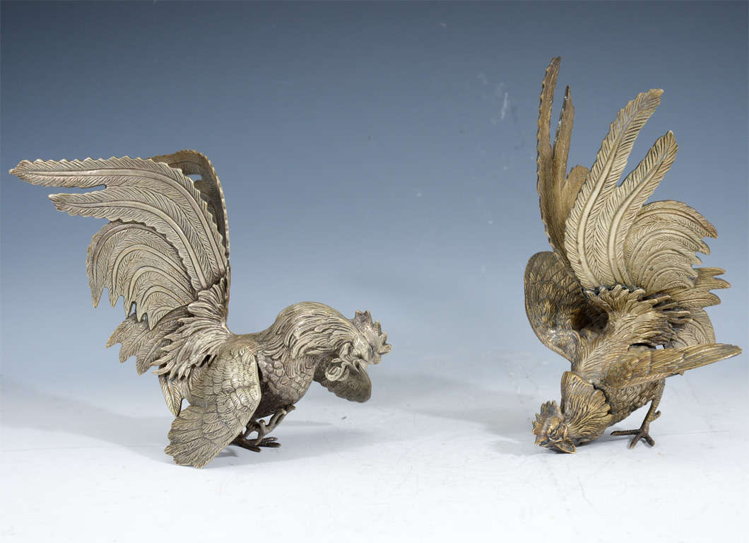 A pair of Japanese gamecock, or fighting roosters, in silvered bronze. Each is in a different pose and has finely rendered detailing throughout their plumage.