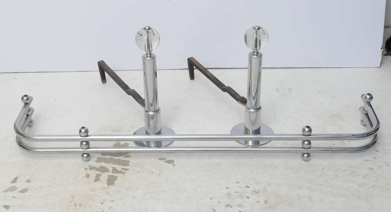 Chrome and glass andirons with a fireplace fender attributed to Donald Deskey.
Fender measures 4.5
