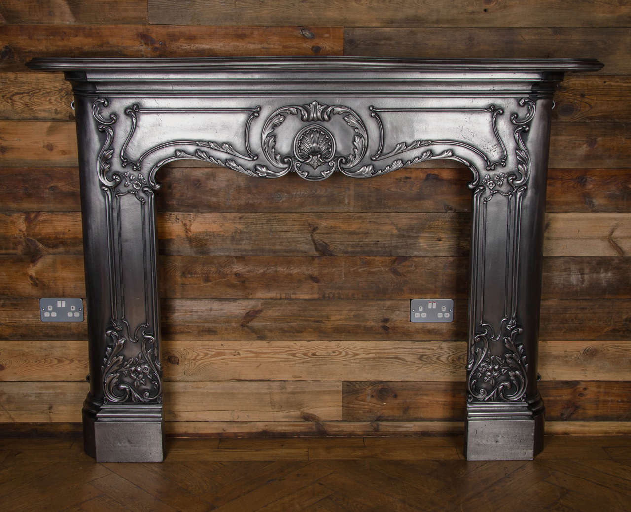 A spectacular cast iron fireplace surround in the Louis XV manner. This reclaimed surround has been polished to accentuate the ornate design and detail. The surround features an elegant serpentine shelf and curved opening. A shell motif on the
