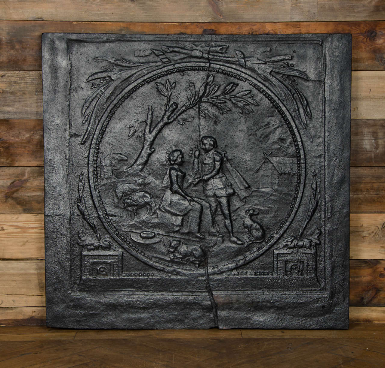 A wonderful original antique fireback dating from the early eighteenth century. This superb Georgian fireback depicts a romantic pastoral scene of a pair of lovers sat under a tree, surrounded by hunting dogs. The fireback has a crack in the centre