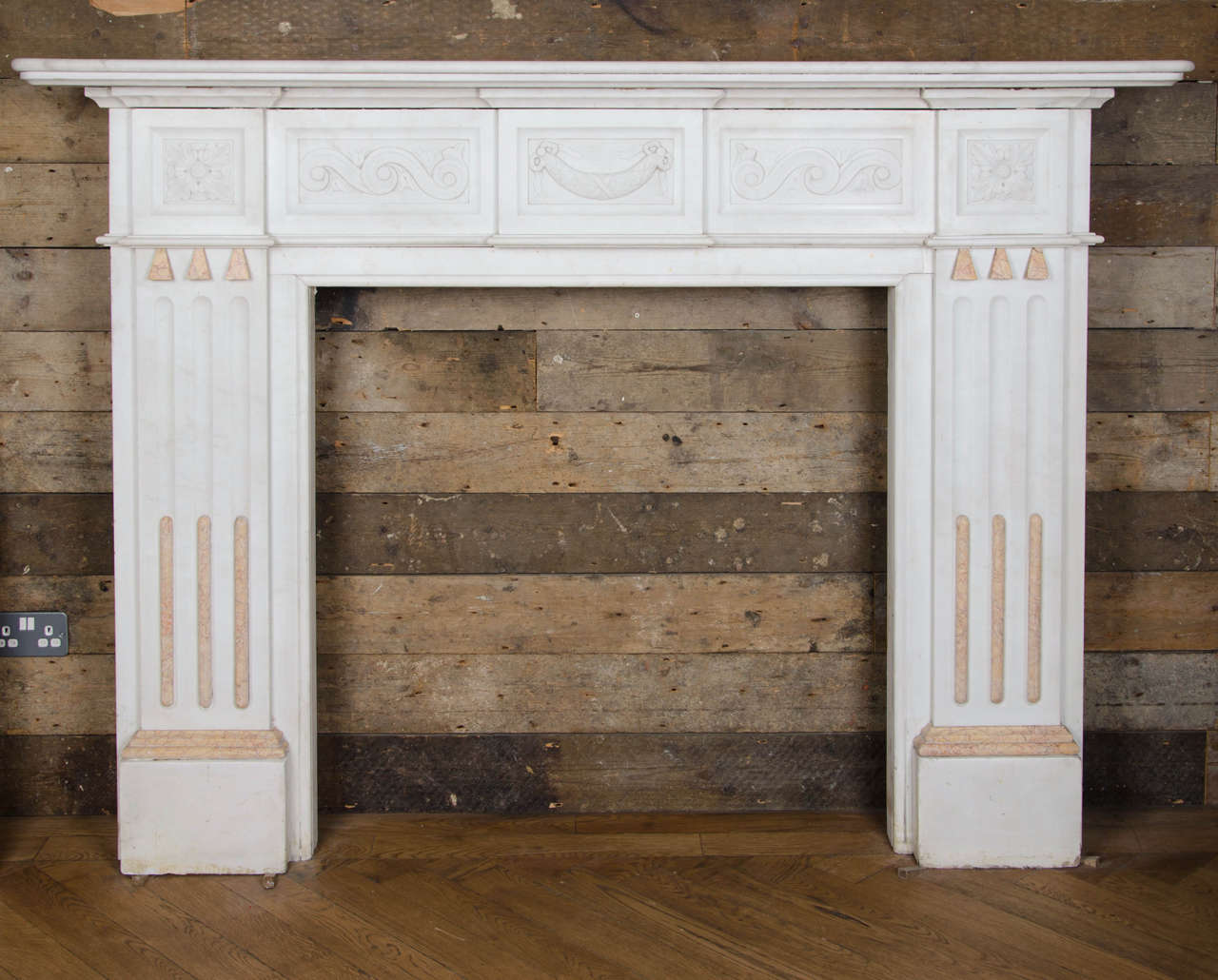 A striking and opulent Victorian fireplace surround made from statuary marble. This antique marble fire surround has elegant, fluted jambs that feature contrasting sienna marble inlay. The frieze has a beautiful, carved vitruvian scroll decoration