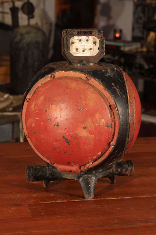 Spherical heavy-gauge cast iron steam regulator with bright red and black paint with various gauges on a meter mounted on top.