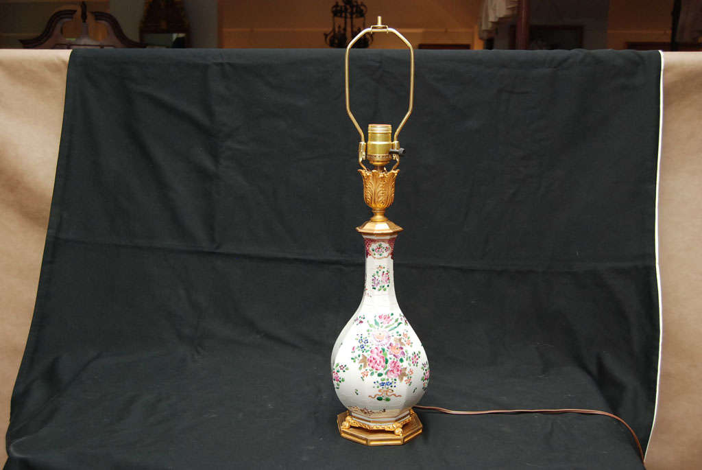 A porcelain vase mounted as a lamp on a gilt bronze base with gilded cap. Scattered floral sprays, diaper decoration at the top of the neck and bianco sopra bianco (raised white on white)

Height to the finial is 25.5