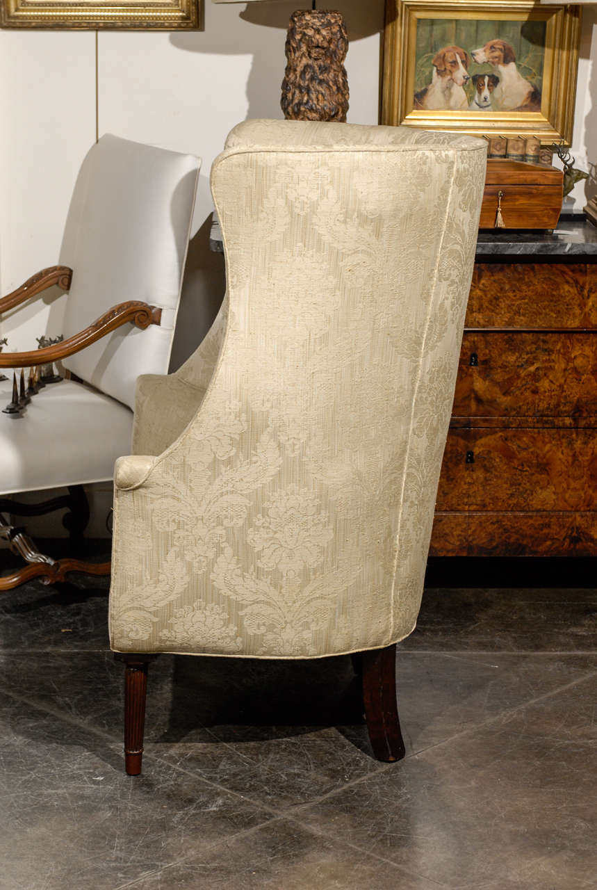 20th Century 1920s Large Barrel Back Upholstered Wing Chair Raised on Four Reeded Legs