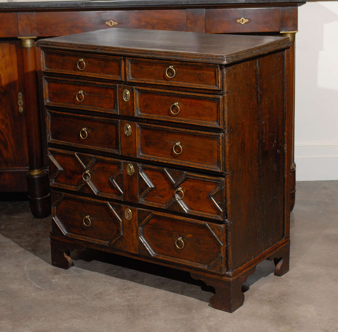 This English oak chest of drawers from the late 18th-early 19th century features a rectangular top with beautiful dovetailing. The chest is adorned with an exquisite geometric front, made of six graduated drawers with the most shallow at the top and